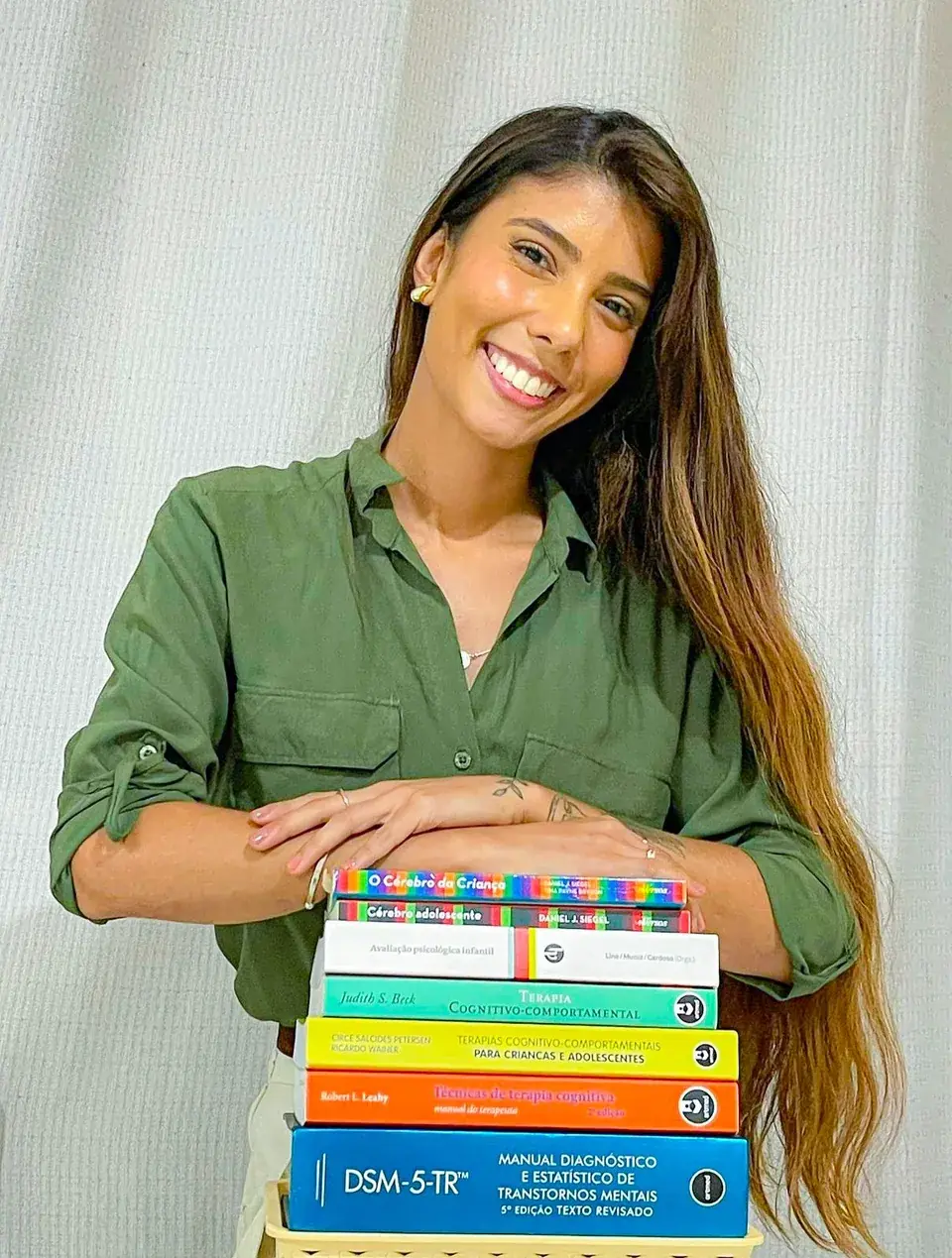 Júlia Machado Duque em seu consultório, ao lado de uma estante de livros